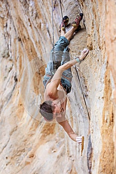 Rock climber gripping a chipped off piece of cliff while climbing a natural cliff