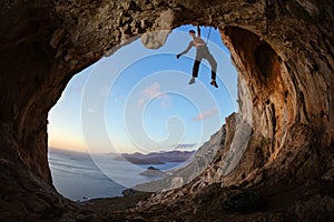 Rock climber gripping handhold on ceiling in cave