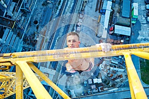 Rock climber hanging on jib of construction crane with one hand