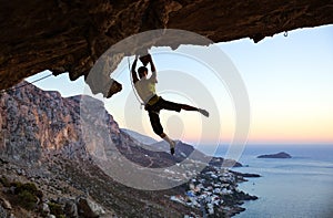 Rock climber jumping on handholds while climbing cliff