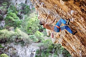 Rock climber on overhanging cliff. Male climber gripping small handholds on challenging route