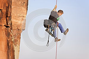 Rock climber and photographer ascending a rock on a rope