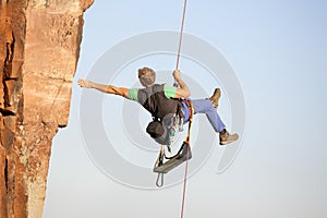 Rock climber and photographer ascending a rock with a rope