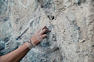 Rock climber& x27;s hand gripping small hold on natural cliff