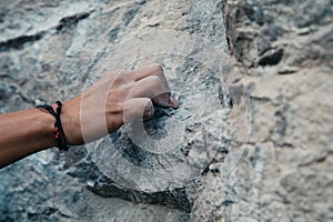 Rock climber& x27;s hand gripping small hold on natural cliff