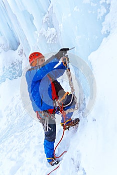 Rock climber screwing ice into glacier surface