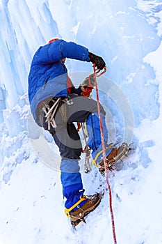 Rock climber screwing ice into glacier surface