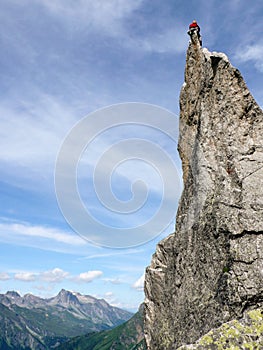 Rock climber sitting atop a sharp rock needle in the Val Bregaglia