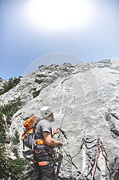 Rock climber stands on a ledge on a rock and belays the partner