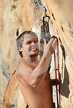 Rock climber struggling to fasten rope to quick-dr