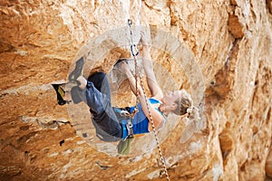 Rock climber struggling to make next movement up