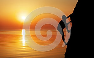 Rock climber at sunset background.