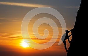 Rock climber at sunset background.