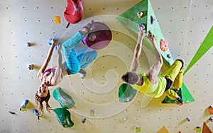 Rock climbers in bouldering gym climbing up overhanging wall