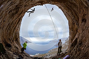 Rock climbers in cave: belayers watching leading climbers