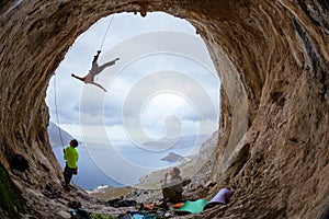 Rock climbers in cave: leading climber swinging on rope after falling of cliff