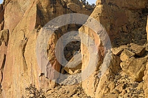 Rock climbers climb a large rock, filmed from the back
