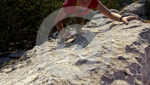 Rock climbing in mountains. A young girl is practicing climbing rock. Climbs up