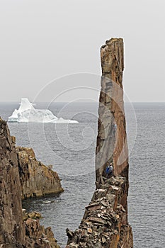 Rock climbing a sea stack with an iceberg in the background