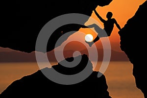 Silhouette man Climbing between rocks with red sky sunset background