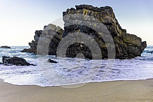 Rock on coastline of sandy Adraga beach, Portugal coast