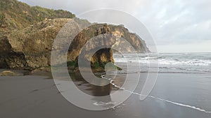 Rock formation arrangement with one single rock looks like a sitting dog animal looking to the sea with reflections and shadows