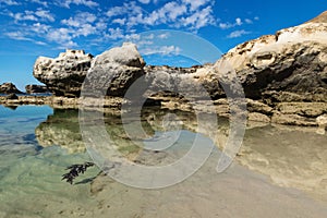 Rock formation with cliff with reflections in the sea at Peterborough beach, Victoria, Australia