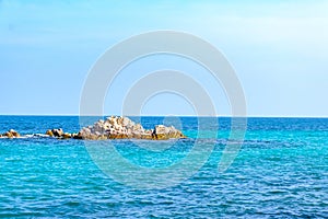 A rock formation in the middle of the sea surrounded by bright blue water