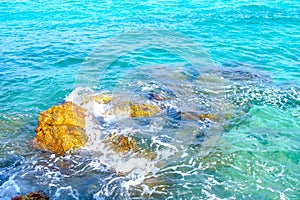 A rock formation in the middle of the sea surrounded by bright blue water