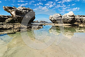 Rock formation an ocean pool with reflections in the sea at Peterborough beach, Victoria, Australia