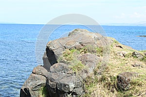 Rock Formation with splashing waves in the Ocean a Blue sky Weather islet with Island Mountain