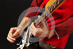 Rock guitarist put fingers for chords on electric guitar on black background