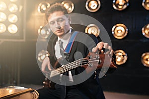 Rock guitarist in suit playing on bas-guitar