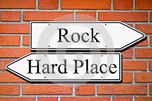 Between rock and hard place signpost concept brick wall