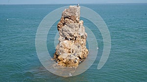 Rock jutting from sea with a seagull perched on it photo