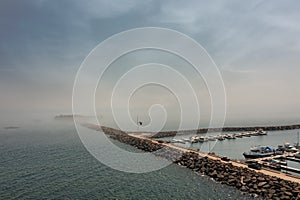 Rock Marina Wall Leads Out to Island Covered by Fog