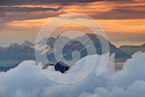 Rock massif of Kamnik Savinja Alps rise above clouds at sunrise