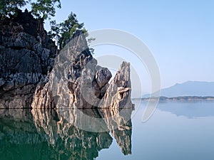 Rock mountain island reflect on lake water with clear blue sky. Calm and peace river