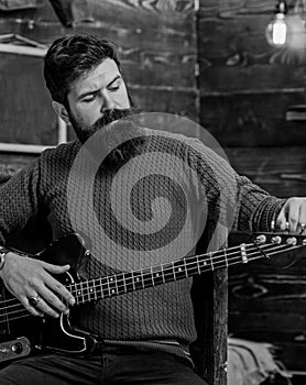 Rock musician with brutal look posing with instrument. Bearded man tuning electric guitar. Man with stylish beard and