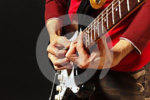 Rock musician with electric guitar on black background