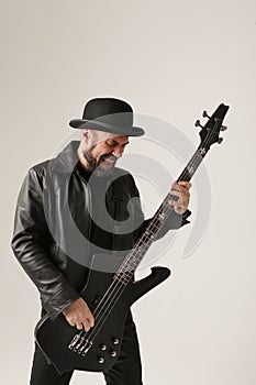 Rock musician. A man with black hat and electric guitar poses at the studio.