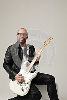 Rock musician. A man plays guitar and posing over white background. Vertical.