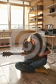 Rock musician playing electric guitar on floor