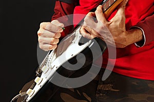 Rock musician put fingers for chords on electric guitar on black background