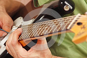 Rock musician put fingers for chords on electric guitar close up