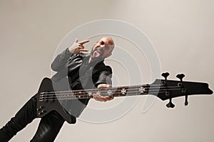 Rock musician with shaved head and electric guitar poses at the studio.