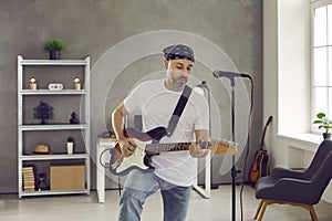 Rock musician standing in rehearsal room and playing music on his electric guitar