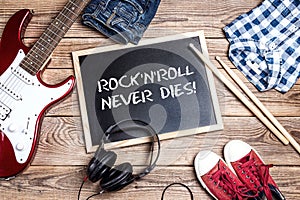 Rock`n`Roll background with blackboard, electric guitar, drumsti