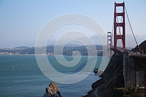 The rock in the ocean between the red Golden Gate bridge and the city of San Francisco