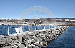 Rock pier in winter juts out into the lake harbor
